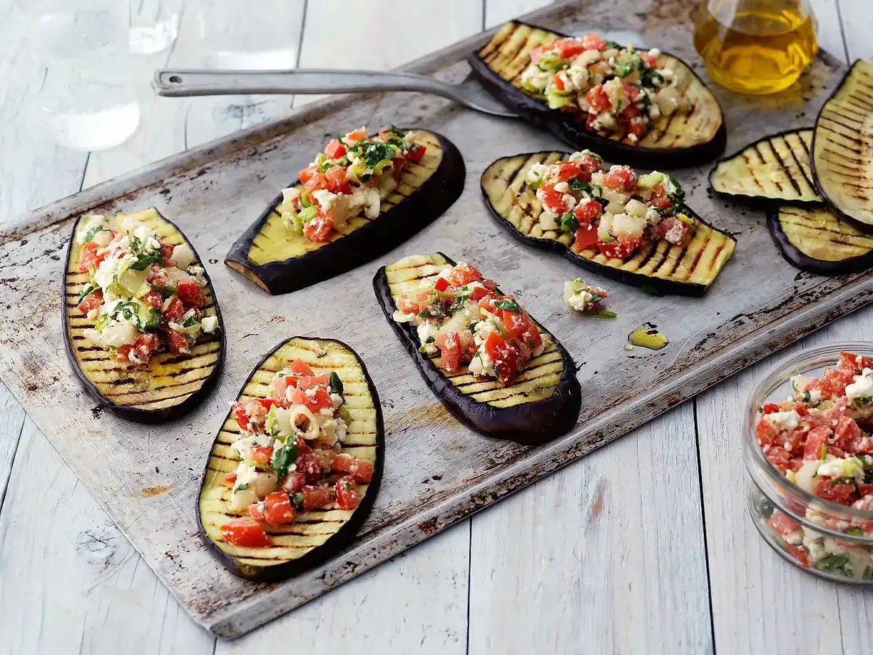 Grilla aubergine halvor toppade med en fr&auml;sch blandning av tomat, fetaost och &ouml;rter. Perfekt som f&ouml;rr&auml;tt eller tillbeh&ouml;r.