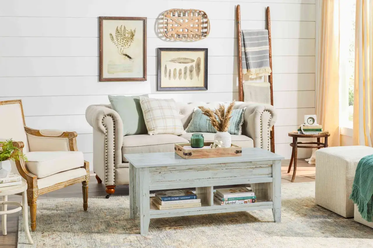 En mysig soffgrupp med shabby chic inredning. En sliten soffa, en tr&auml;stege med pl&auml;dar och en kaffeb&auml;nk med b&ouml;cker.