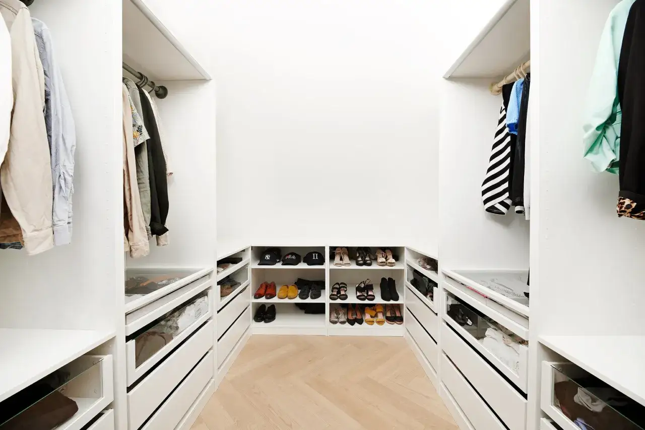 En stilren walk-in-closet med vita PAX-garderober, fulla av kläder och skor. Perfekt pax garderob inspiration för ordning och reda.