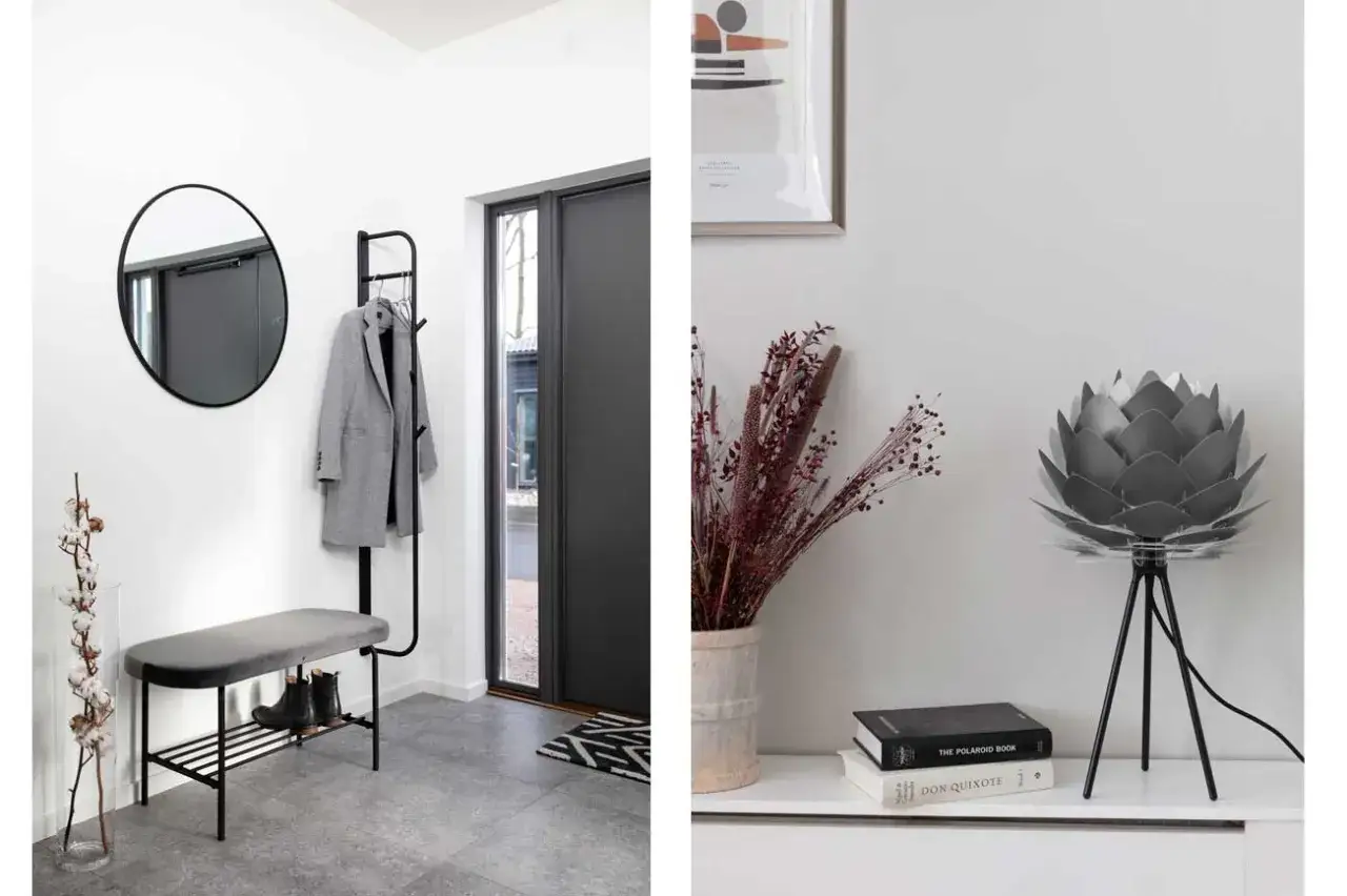 En mysig hall med en gr&aring; kappa p&aring; kl&auml;dh&auml;ngare, en rund spegel och en sittb&auml;nk. Till h&ouml;ger en lampa formad som en blomma och en vas med torkade blommor.