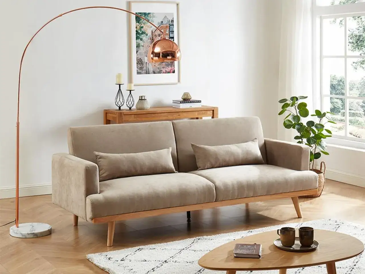 En soffa med pastell inredning, kopparlampa och en grön växt vid fönstret.