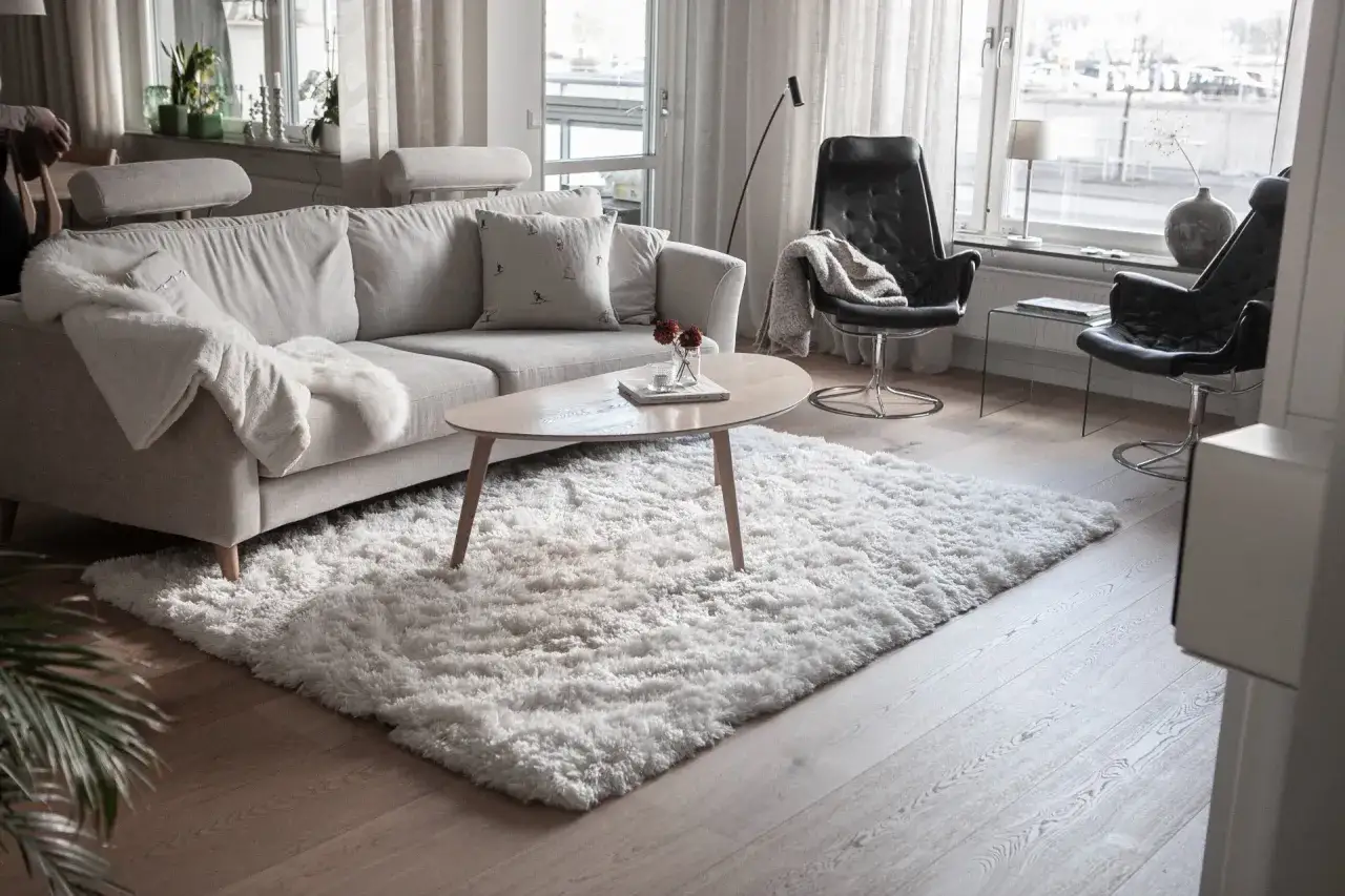 En mjuk, fluffig matta till grå soffa skapar en mysig känsla i vardagsrummet.