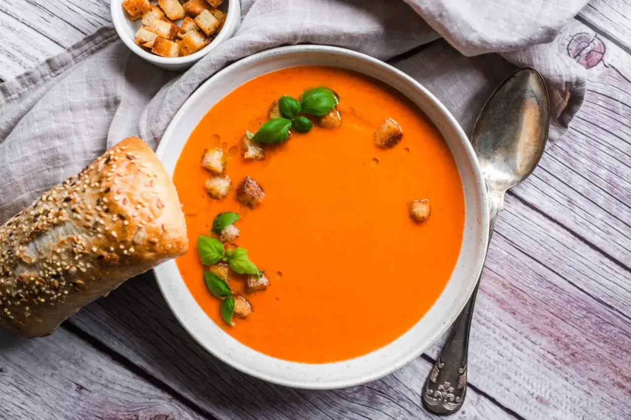 En sk&aring;l med orange gazpacho, toppad med krutonger och basilika. Serveras med ett gott br&ouml;d. Ett perfekt gazpacho recept f&ouml;r sommaren.
