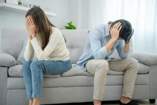 Ett par sitter på en soffa, båda med händerna för ansiktet. Mannen verkar förtvivlad, kanske på grund av att han är notorisk otrogen.