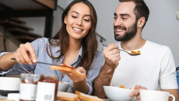 Ett leende par äter frukost tillsammans, en stund att hitta tillbaka till varandra i vardagen.