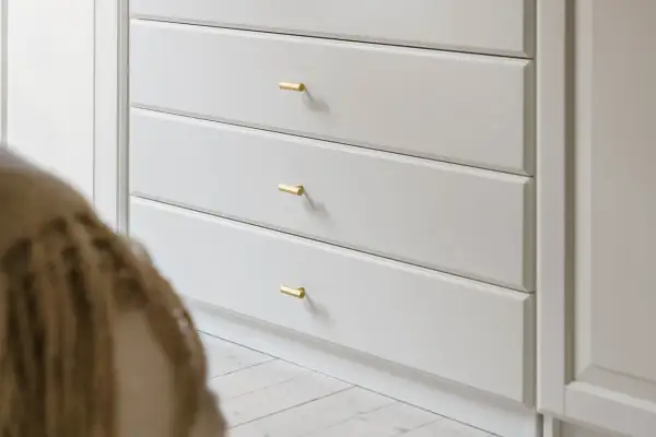 En ljusgrå byrå med mässingshandtag. Enkel design som kan passa i många hem, ett smart sätt att få till en lyxig känsla med ett litet bestå hack.