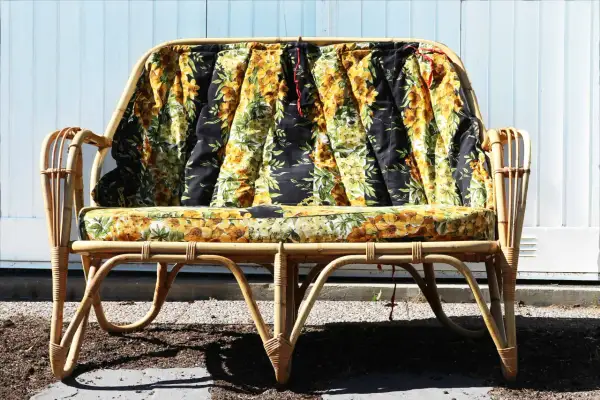 En soffa i konstrotting med blommiga dynor. Perfekt för att måla och skapa en unik möbel.
