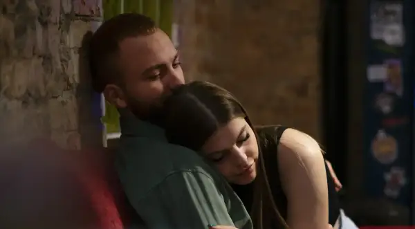 En man kysser en kvinna på pannan. De sitter nära varandra, en bild av trygghet och kärlek, som visar grundstenar i en relation.