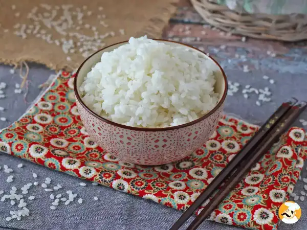 Perfekt sushiris i en vacker skål, redo för ditt sushirecept. Ätpinnar ligger bredvid.